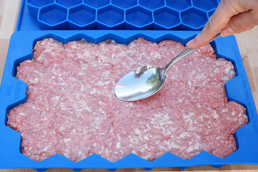 Spreading meatball mix into the Meatball Master